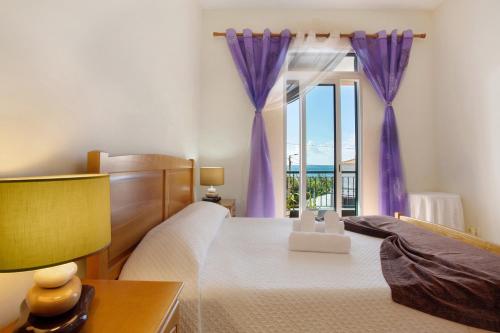 a bedroom with a bed and a window with purple curtains at Casa Orquidea T3 in Ponta do Sol