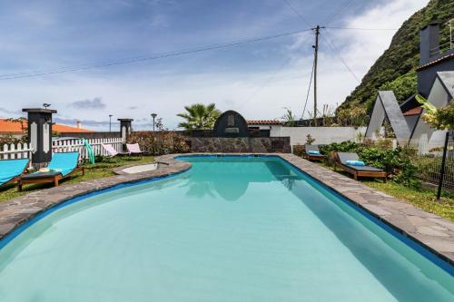 a swimming pool with chairs and a house at Cork House - Fernandes Cottage in Ponta Delgada