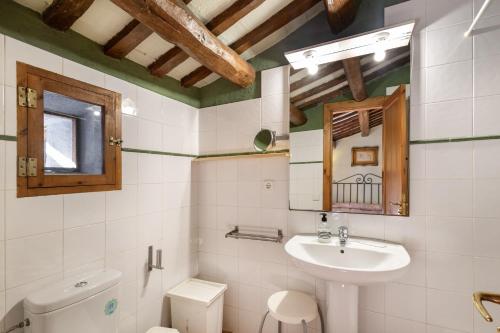 a bathroom with a sink and a toilet and a mirror at Cal Contra in Gélida