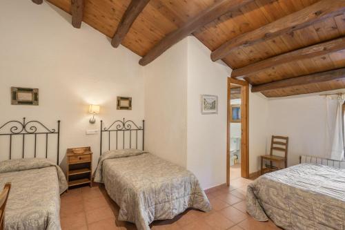 a bedroom with two beds and a wooden ceiling at Cal Contra in Gélida