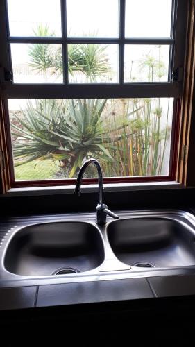 a kitchen sink in front of a window at De Baixo Da Ponte in Biscoitos