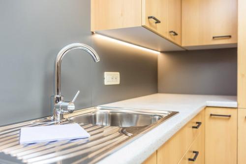 a kitchen with a stainless steel sink and wooden cabinets at Schildberghof Schlernblick in Kastelruth