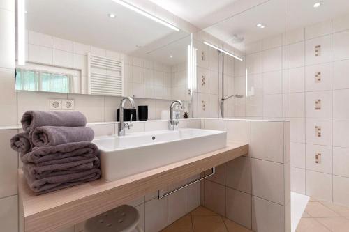 a white bathroom with a sink and a mirror at Landeckhof in Oberwolfach