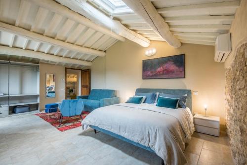 a bedroom with a bed and two blue chairs at Brotes Appartamento Ciliegio in Sovicille