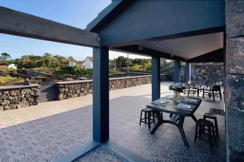 a patio with a table and chairs and a stone wall at Adega do Portinho Velho in Piedade