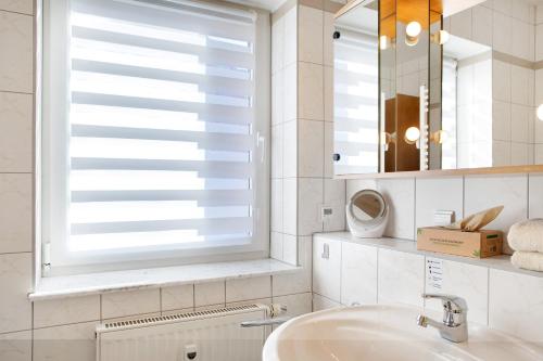 a bathroom with a sink and a window with blinds at Ferienwohnung Tannenblick 7-4 in Oberhof