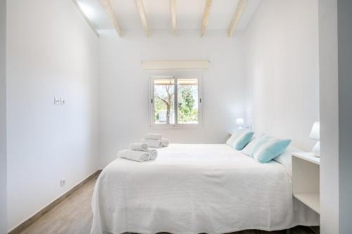 a white bedroom with a large white bed with blue pillows at Ses Oliveres in Pollença