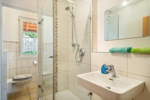 a white bathroom with a sink and a shower at Ferienwohnung Buchmann in Deggenhausertal
