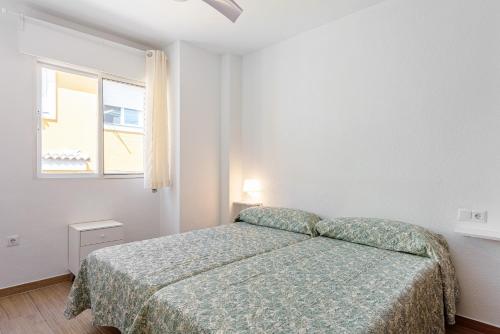 a white bedroom with a bed and a window at Casa Mar de frente in Málaga
