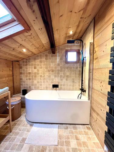a bath tub in a bathroom with wooden walls at Chalet Mouflon - Vue lac imprenable in Thollon