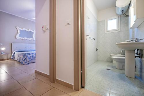 a bathroom with a sink and a toilet and a bed at Appartamento Andromeda B2 in Bibione