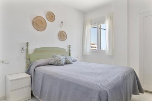 a white bedroom with a bed and a window at Apartamento a pie de playa in Barbate