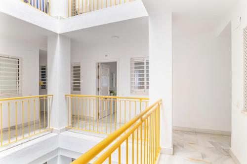 a staircase in a house with white walls and yellow railings at Apartamento a pie de playa in Barbate