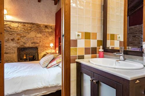 ein Badezimmer mit Waschbecken, ein Bett und einen Kamin in der Unterkunft Morouzos in O Porto de Espasante