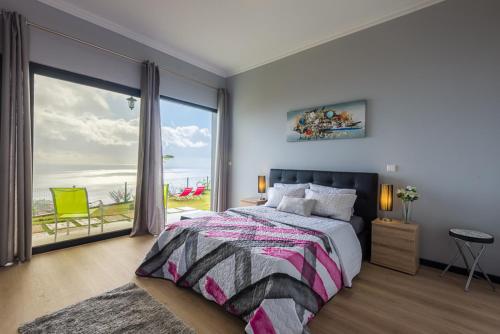 a bedroom with a bed and a large window at Casa do Louro in Arco da Calheta