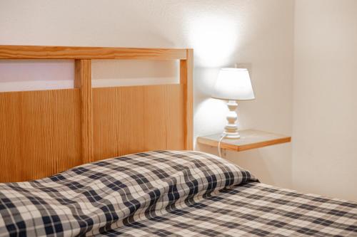 a bed with a checkered blanket and a lamp at La Capannuccia A in Ansedónia