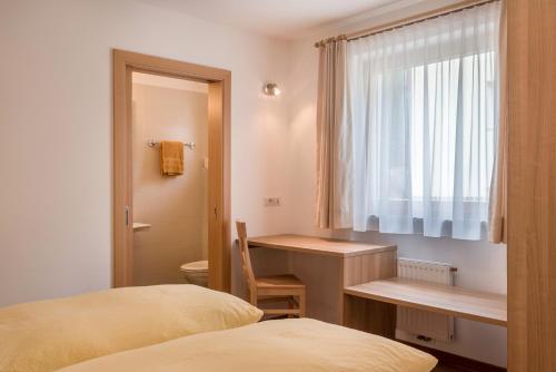 a bedroom with a desk and a bed and a window at Hilber Fermeda in Villnoss