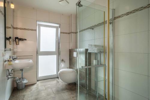 a bathroom with a toilet and a glass shower at Familien-Apartment 1 in Meersburg