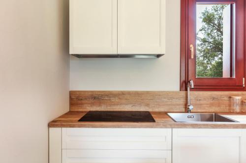 a kitchen with white cabinets and a sink and a window at La casa di Debora in San Teodoro