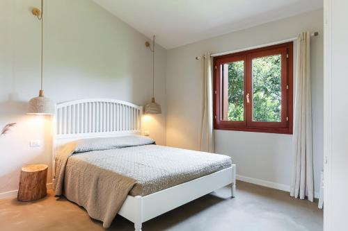a white bedroom with a bed and a window at La casa di Debora in San Teodoro