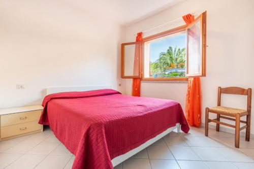 a bedroom with a bed and a window and a chair at A.I.R. Isola Rossa Borgo di Mare in Isola Rossa