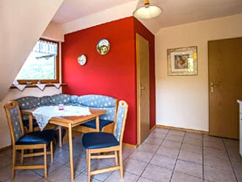 a room with a table and chairs and a red wall at Ferienwohnung Echle in Oberharmersbach