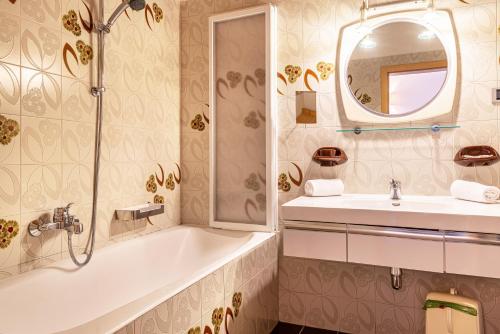 a bathroom with a tub and a sink and a mirror at Sabina Dolomites Latsche in Alpe di Siusi