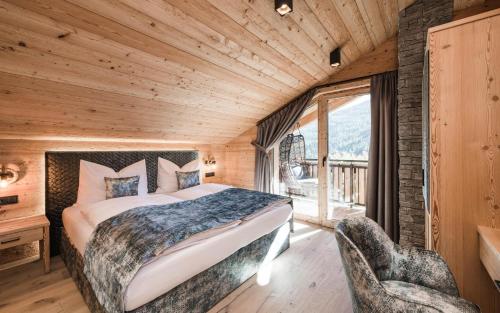 a bedroom with a bed and two chairs in a room at New Chalet Brunegg Weissenbach in Rio Bianco