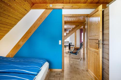a bedroom with a blue wall and a wooden ceiling at Haus Grünblick in Münstertal