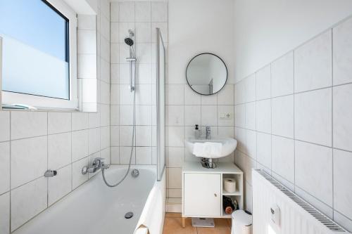a bathroom with a sink and a tub and a mirror at Ferienwohnung mit Dachterrasse in Heide