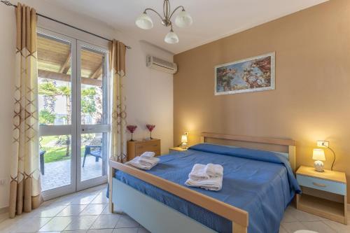 a bedroom with a blue bed with towels on it at Villa Forino Ragusa in Santa Maria del Focallo