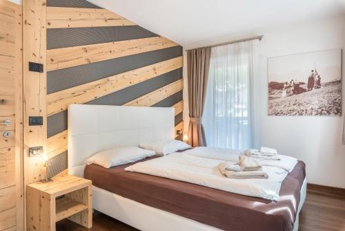 a bedroom with a bed and a wooden wall at Appartamento Ciasa in Pozza di Fassa