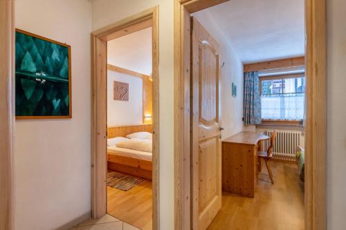 a bedroom with a bed and a desk and a mirror at Apartment Pordoi in Campitello di Fassa