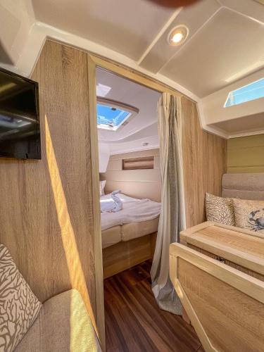 a small caravan with a bed and a tv in it at Hausboot Segelyacht Nui in Burgtiefe auf Fehmarn 