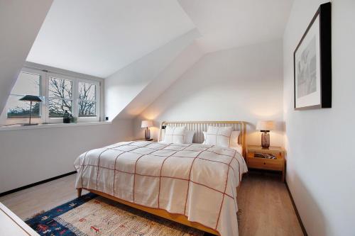 a white bedroom with a bed and a window at Appartement in Wangen im Allgäu