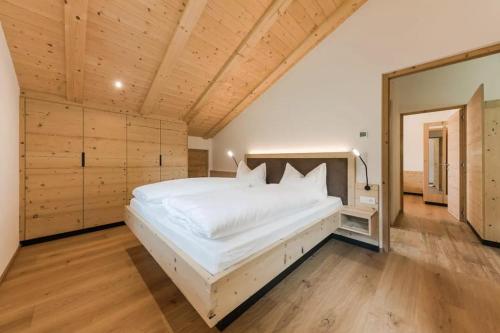 a large white bed in a room with wooden walls at Natur Suite Edelweisshof App Georg in Chiusa
