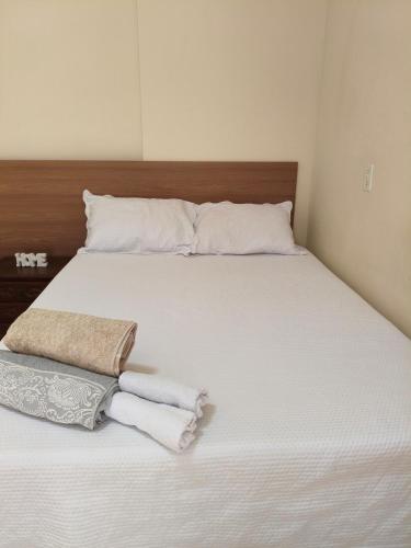 a bed with white sheets and towels on it at 800m da UFV, 500m da rodoviária, Wi-Fi, TV smart. in Viçosa