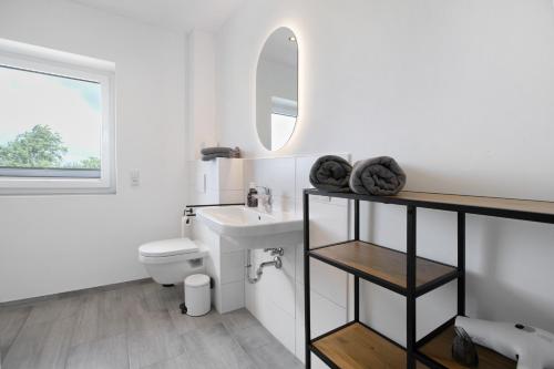 a white bathroom with a sink and a mirror at Ferienhaus Ebbe in Schülp