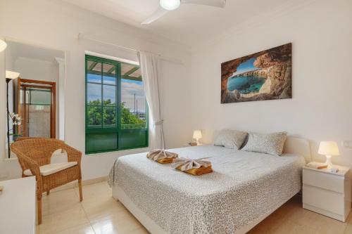 a bedroom with a bed and a chair and a window at El Gin in Playa Blanca