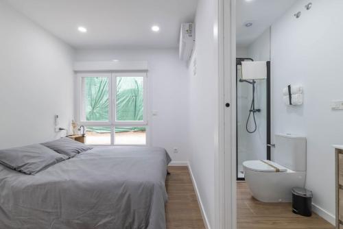 a bedroom with a bed and a tub and a window at Aptos Ría San Cosme Aurora in Bendimón