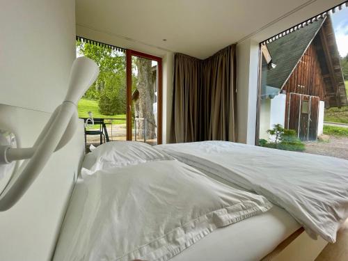 a white bed in a bedroom with a large window at Lippenhof - Unter der Linde in Unterkirnach