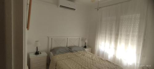 a white bedroom with a bed and a window at Casa Jazmin in Roses
