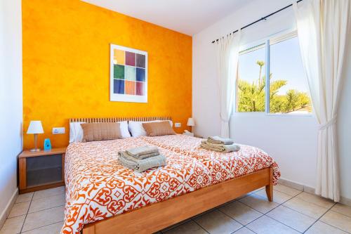 a bedroom with a bed with a yellow wall and a window at Villa Individual Peñíscola in Peniscola