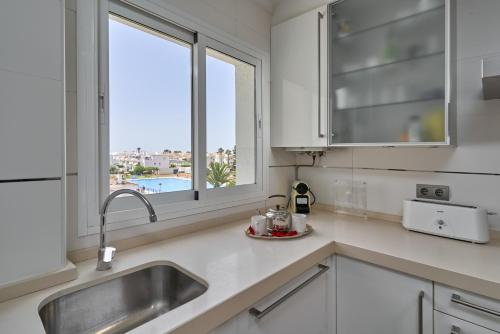 a white kitchen with a sink and a window at La Mejor in Torrox