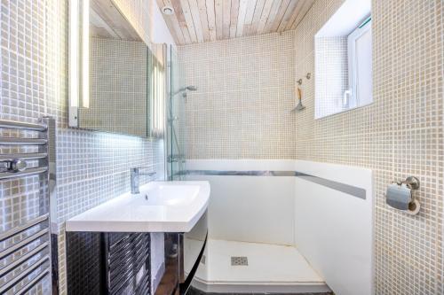 a white bathroom with a sink and a tub and a mirror at Maison vacances La Terrière in La Tranche-sur-Mer