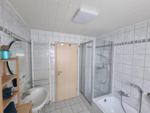 a bathroom with a shower and a tub and a sink at Ferienwohnung Biosphärenblick in Münsingen