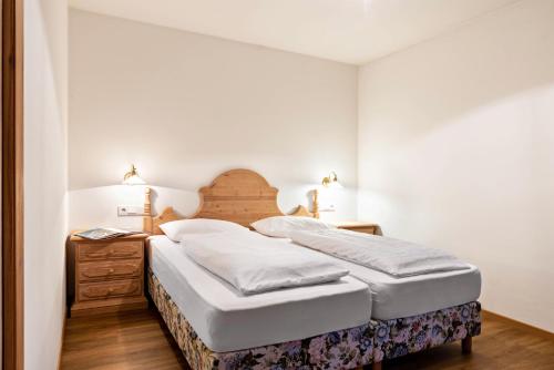 a bedroom with a bed with a wooden headboard and a night stand at Cesa Valeria App Sonia in Ortisei