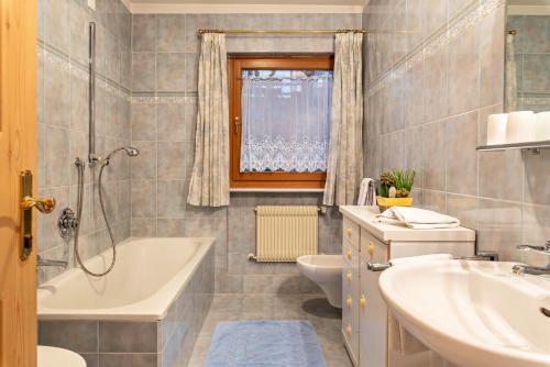 a bathroom with a tub and a toilet and a sink at Cesa Valeria App Sonia in Ortisei
