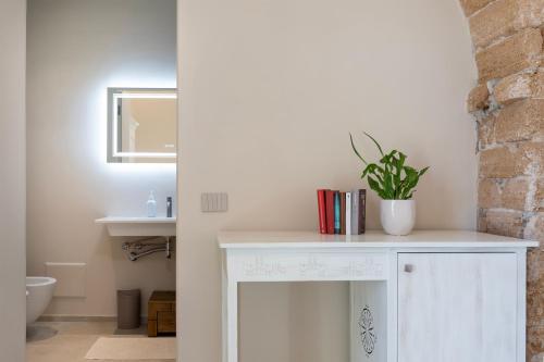 a bathroom with a white vanity with a plant on it at Dimora Sella Rooms in Alghero