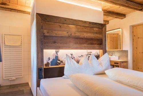 a bedroom with a large white bed with a wooden headboard at Hatzeshof Heustadel in Laion